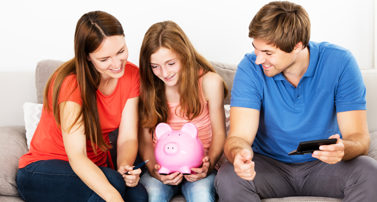 Family sitting closely together while child holds a piggy bank