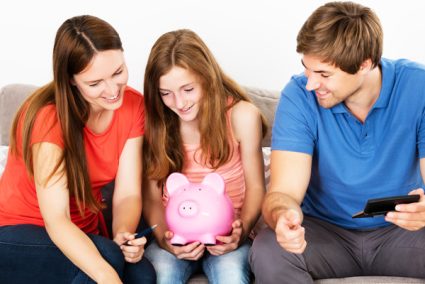 Family sitting closely together while child holds a piggy bank