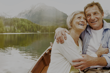 Smiling couple embracing in a boat on a lake with mountains in the background